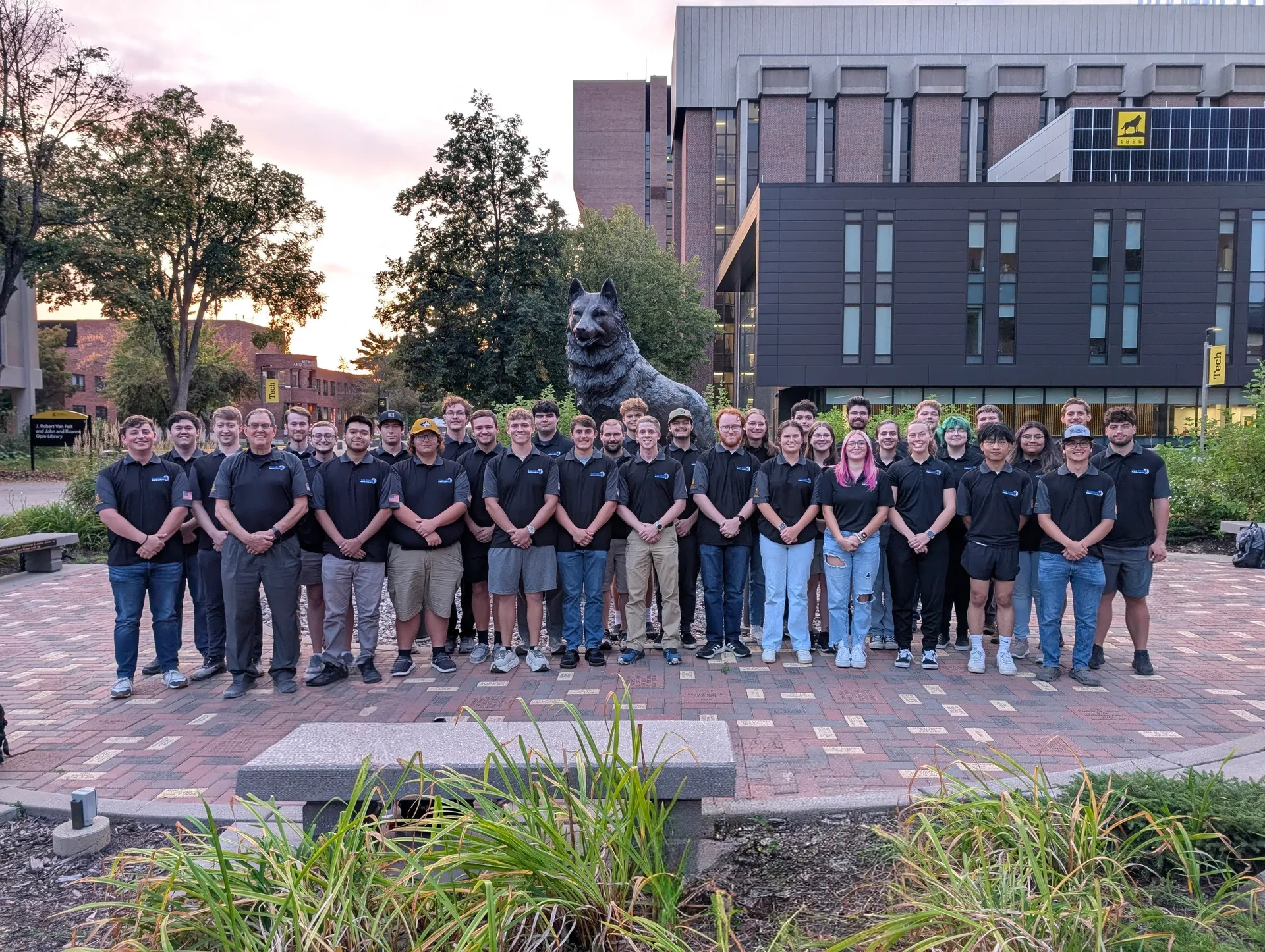 The Blue Marble Security Enterprise team standing together infront of the Husky Statue.